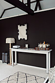 White console, mirror above on a black wall in a modern ambience