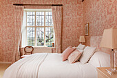 Schlafzimmer mit Tapeten mit rosa Blumenmuster und Blick auf den Garten