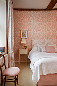 Bedroom with pink floral pattern wallpaper and matching bed linen