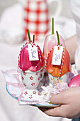 Decorated Easter eggs with name tag on plate held in hands