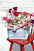 Bouquet of spring flowers in bag on red chair