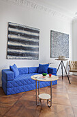 Minimalistisches Wohnzimmer mit blauem Sofa und moderner Kunst an der Wand