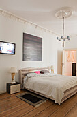 Doppelbett in Altbau-Schlafzimmer mit Stuckarbeit und Holzdielenboden