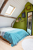 Attic bedroom with green accent wall and skylight