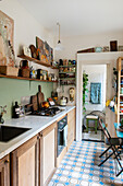 Schmale Küche mit Holzschränken und blau gemustertem Boden