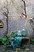 Seating area with wooden bench and fairy lights in front of brick wall in courtyard