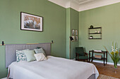 Double bed and sitting area in the bedroom with green walls