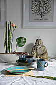 Keramikgeschirr im Kintsugi-Design mit Buddha-Statue im Hintergrund
