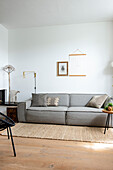 Minimalistisches Wohnzimmer mit grauem Sofa, Juteteppich und Wanddekoration