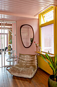 Leather armchair in eclectic living room with pink walls and yellow window frames