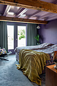 Bedroom with exposed wooden beams and purple walls