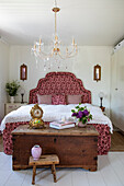Bedroom with large bed, crystal chandelier and antique wooden chest
