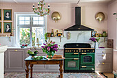 Country-style kitchen with green hob and floral decoration on the table