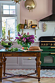 Küche mit grünem Herd, grauen Schränken und Blumenstrauß auf Vintage-Tisch