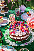 Garden party with richly decorated chocolate cake on a glass plate