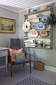 Holzregal mit Geschirr und Textilien in einer Vintage-Ecke mit Stuhl