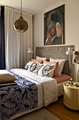 Schlafzimmer mit gemustertem Kopfteil, blau-weißer Bettwäsche und Hängeleuchte