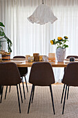 Esstisch mit Sonnenblumen in Vase und braunen Stühlen