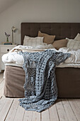 Bedroom with upholstered bed and crocheted blue blanket