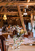 Rustic wedding banquet in a barn with wooden tables and floral decorations