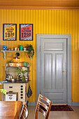 Vintage dining area with yellow wall panels and retro kitchen shelf