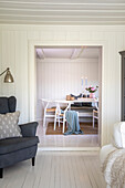 Blick vom Wohnzimmer ins Esszimmer in skandinavischem Design mit weißer Holzvertäfelung