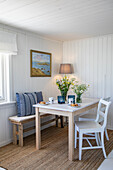Small country-style dining room with white wall paneling and rustic furniture