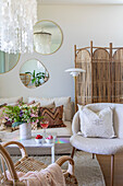 Living room with rattan room divider, pendant lights and mirror decorations