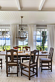 Dining area with wooden table, classic chairs and chandelier, sea view
