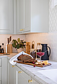 Light grey kitchen cabinets with golden handles, breakfast on serving board