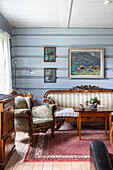 Rustikales Wohnzimmer mit antiken Möbeln und blauen Wandpaneelen