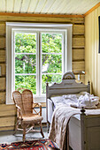 Rustikales Schlafzimmer mit Rattanstuhl und traditionellem Bett