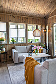 Grey sofas and wooden table with bouquet of flowers in wood-panelled living room