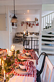 Weihnachtlich gedeckter Tisch mit Kerzen und Tannenzweigen in weißem Esszimmer