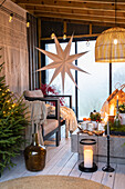 Weihnachtlich dekorierter Raum mit Tischfeuer, Kerzen, Sesseln und Decken