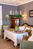 Gedeckter Tisch und klassische Sofaecke im traditionell eingerichteten Wohnzimmer