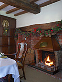 Rustic dining area with open fireplace, traditional wood panelling, bricks and Christmas decorations