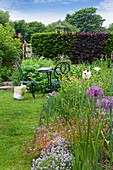 Sitzbereich mit Metallmöbeln in blühendem Garten