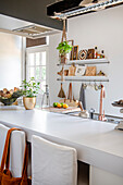 Kitchen with white worktop, hanging herb pot and copper faucet