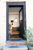 Open front door to an entrance area with antique sofa and mirror