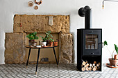 Wood-burning stove next to stone wall and plants on side table