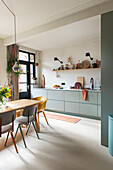 Modern kitchen with green base cabinets and dining area with different chairs