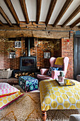 Living room with fireplace, bricks, colourful patterned textiles and exposed beams