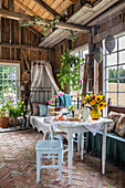 Gartenhaus mit gedecktem Tisch, Pflanzen, frischen Sommerblumen und Himmelbett