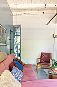 Living room with pink sofa, light blue wood paneling and leatherette chair