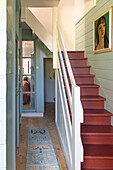 Staircase with red-painted steps and art on the wall