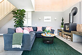 Modern living room with blue sofa, pink cushions and green carpet