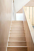 Staircase in light-colored wood with a minimalist design and light-colored walls