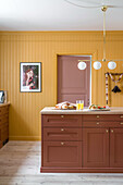 Kitchen with yellow wood paneling and terracotta-colored kitchen island