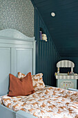 Children's room with blue-painted wooden paneling and bed with horse bed linen